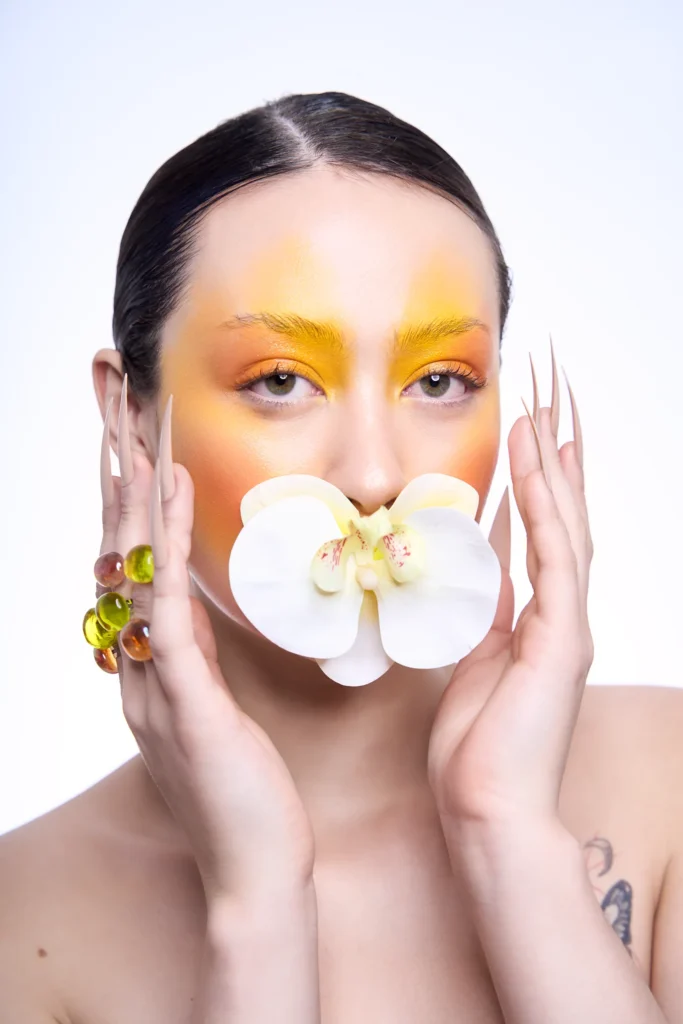 Fotografía artística de una modelo con maquillaje amarillo y una orquídea, realizada en el estudio creativo VR Creative Studio de Mallorca.