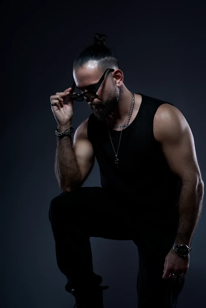 DJ Lahox posando de rodillas con gafas de sol para su sesión de marca personal.